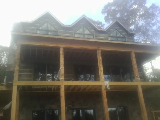 Dormers and porch framing on a large log home under construction — Roof Coating work by our crew in Lewiston